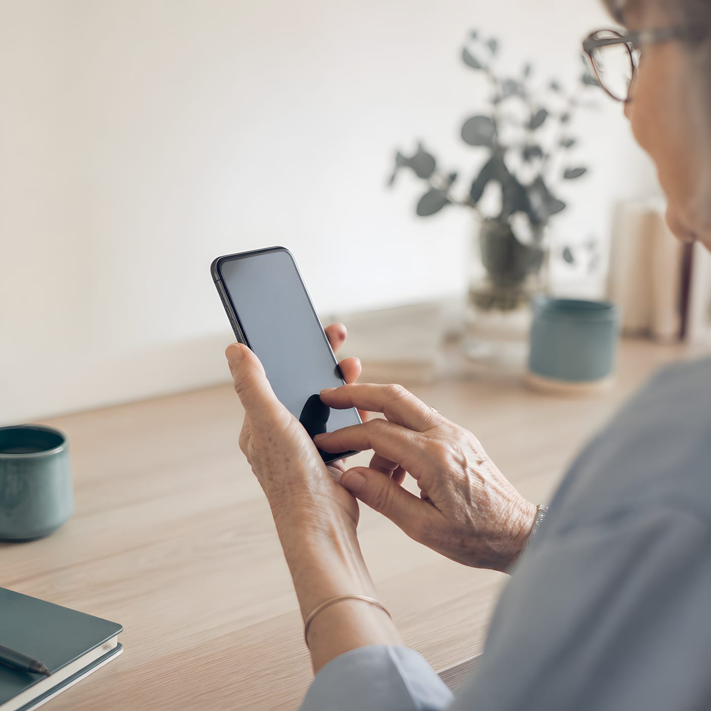 Hände einer älteren Person richten ein Smartphone ein